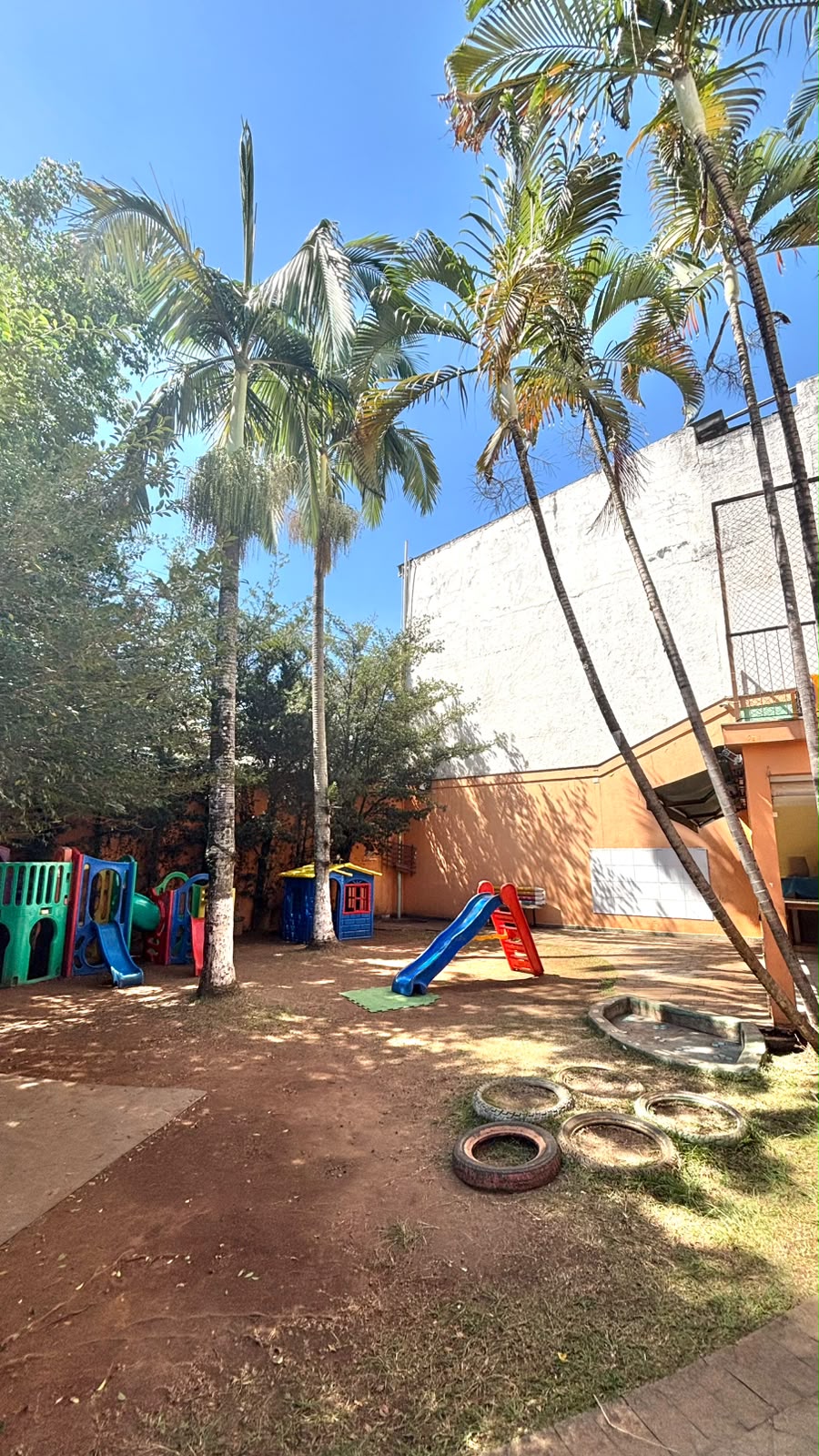 Área externa arborizada da RUAH com playground colorido