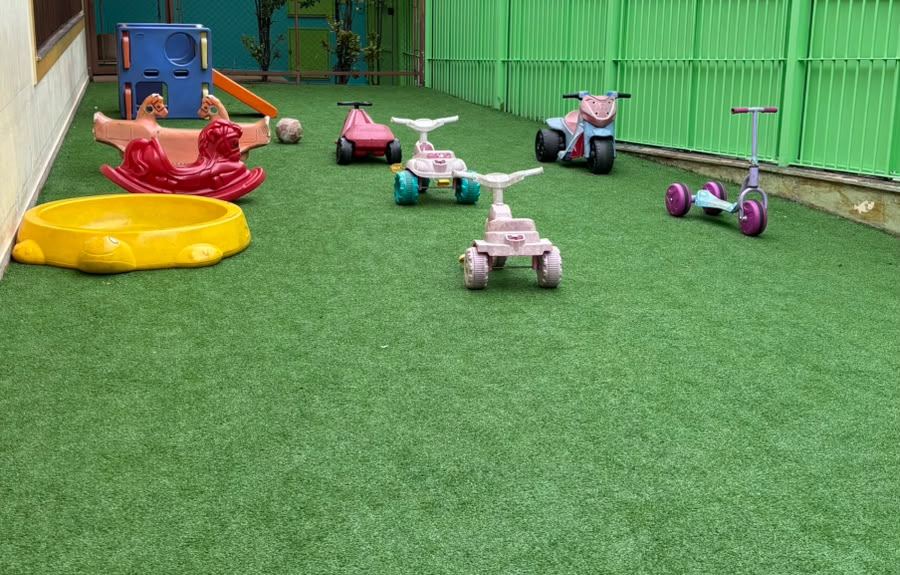 Pátio externo da RUAH com carrinhos e patinetes sobre a grama sintética