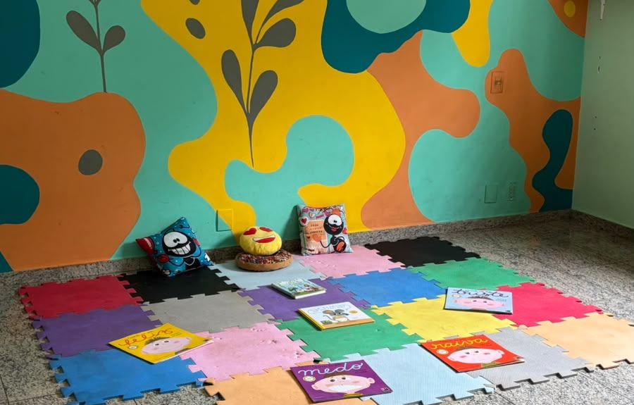 Sala de atividades da RUAH, com parede colorida ilustrada e tapete de atividades