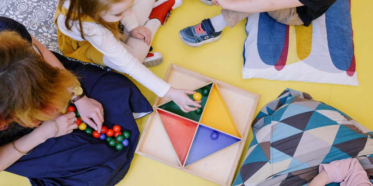 Crianças e educadora brincando juntas com brinquedo de encaixar cores